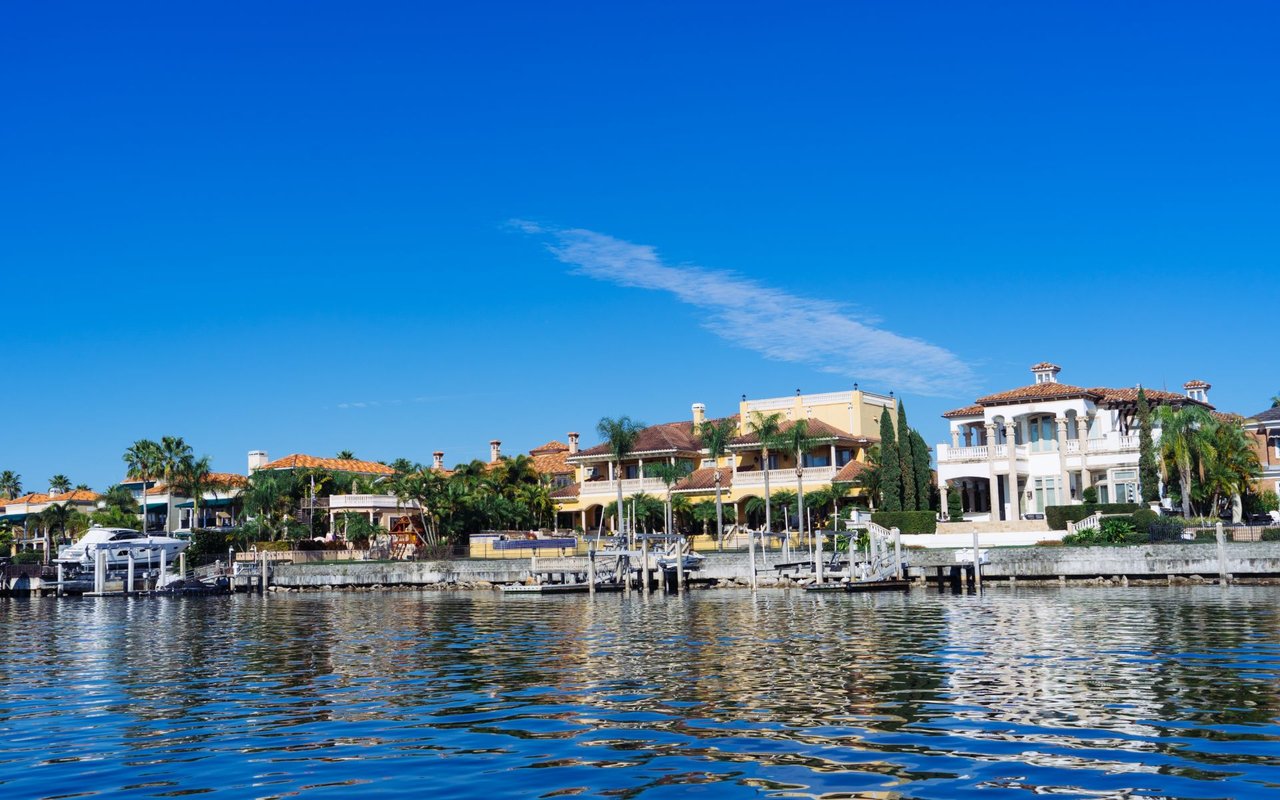 Waterfront homes with private docks and palm trees along a calm channel.