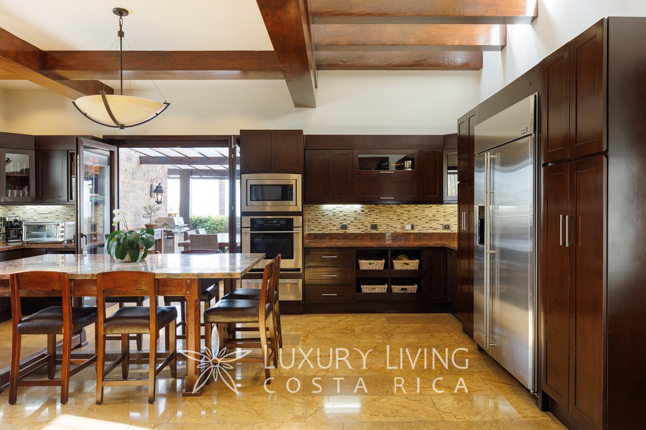 Kitchen with dark wood cabinetry, stainless-steel appliances, and exposed ceiling beams.