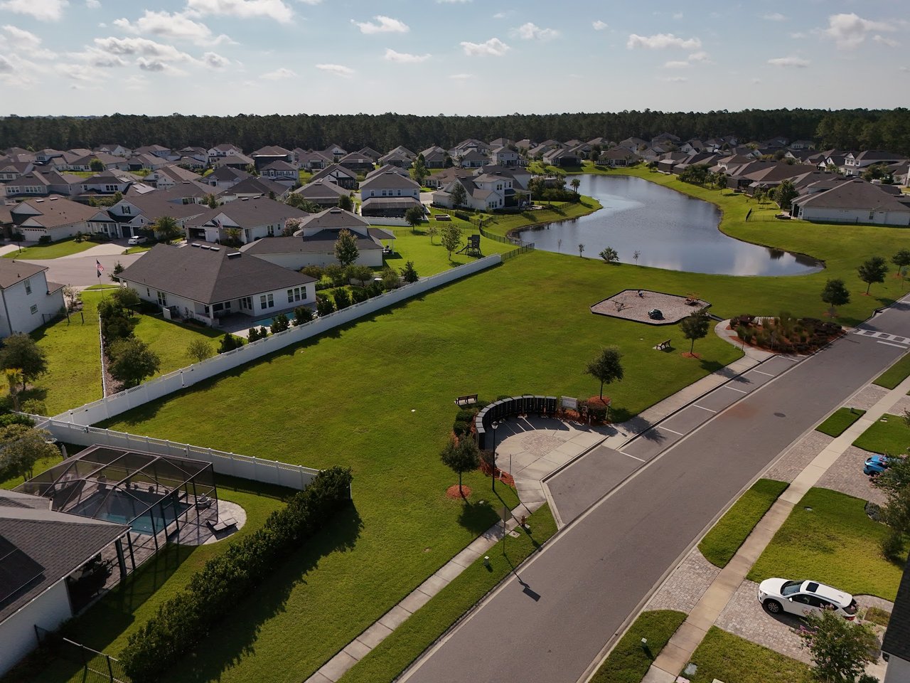 Aerial view of homes around a pond and grassy community park.
