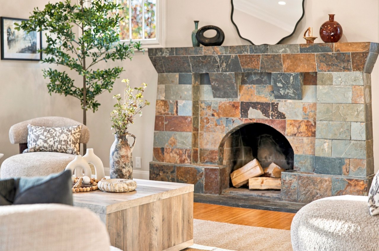 Living room with a multicolored stone fireplace, pale chairs, and a wood coffee table.