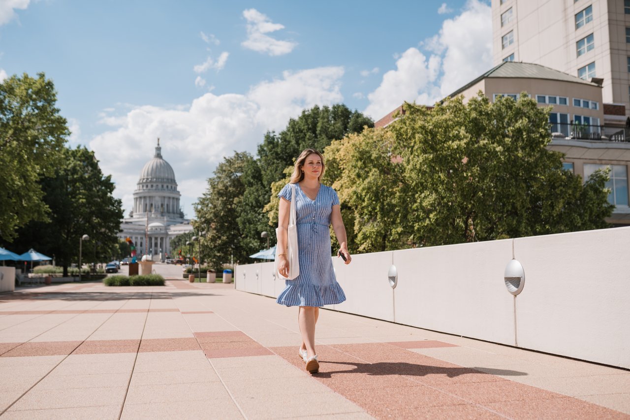 Cait Berry of Insiders Realty walking through downtown Madison with the Wisconsin State Capitol visible in the background, representing the kind of local guidance that helps relocation buyers understand Madison from the ground level.