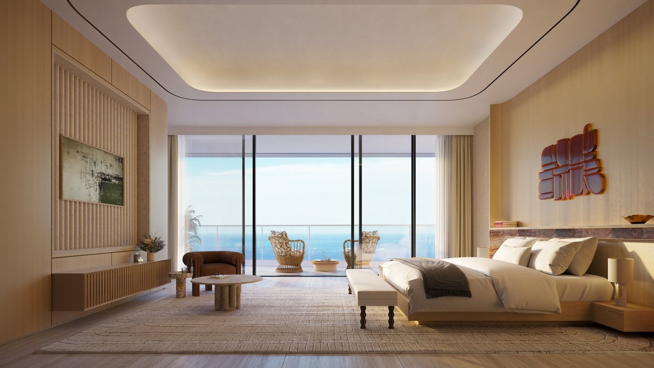 Luxury bedroom with floor-to-ceiling windows overlooking the ocean and a furnished balcony.