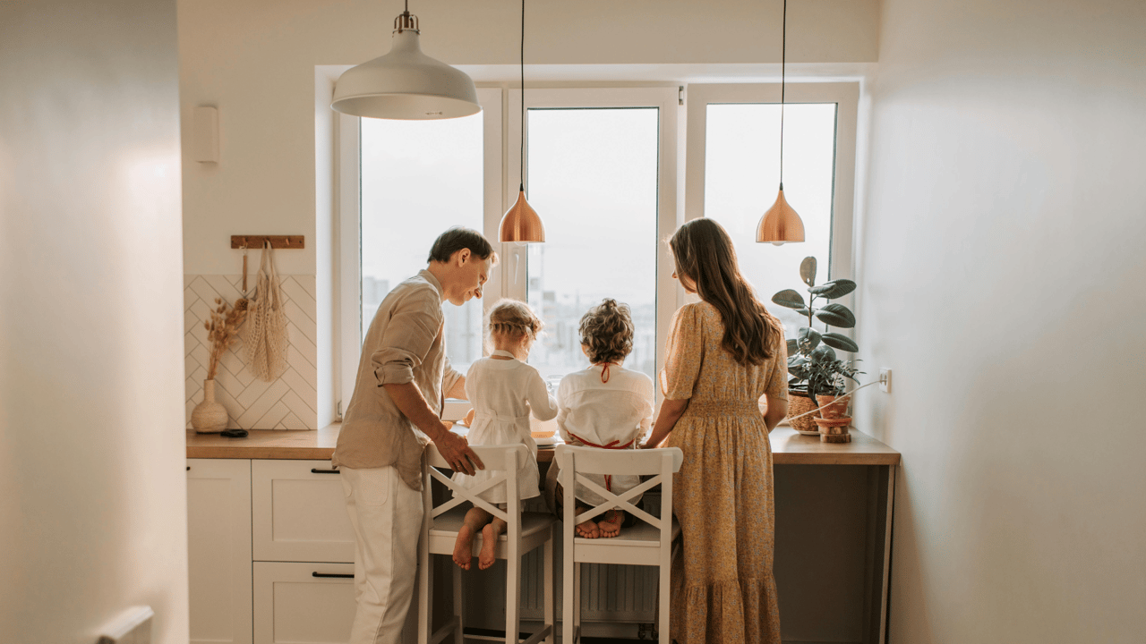 A family of four gathers in a sunlit kitchen, enjoying quality time together—capturing the warmth, connection, and everyday moments that make Gainesville real estate more than just an investment. Gainesville FL realtor Anna Olcese.