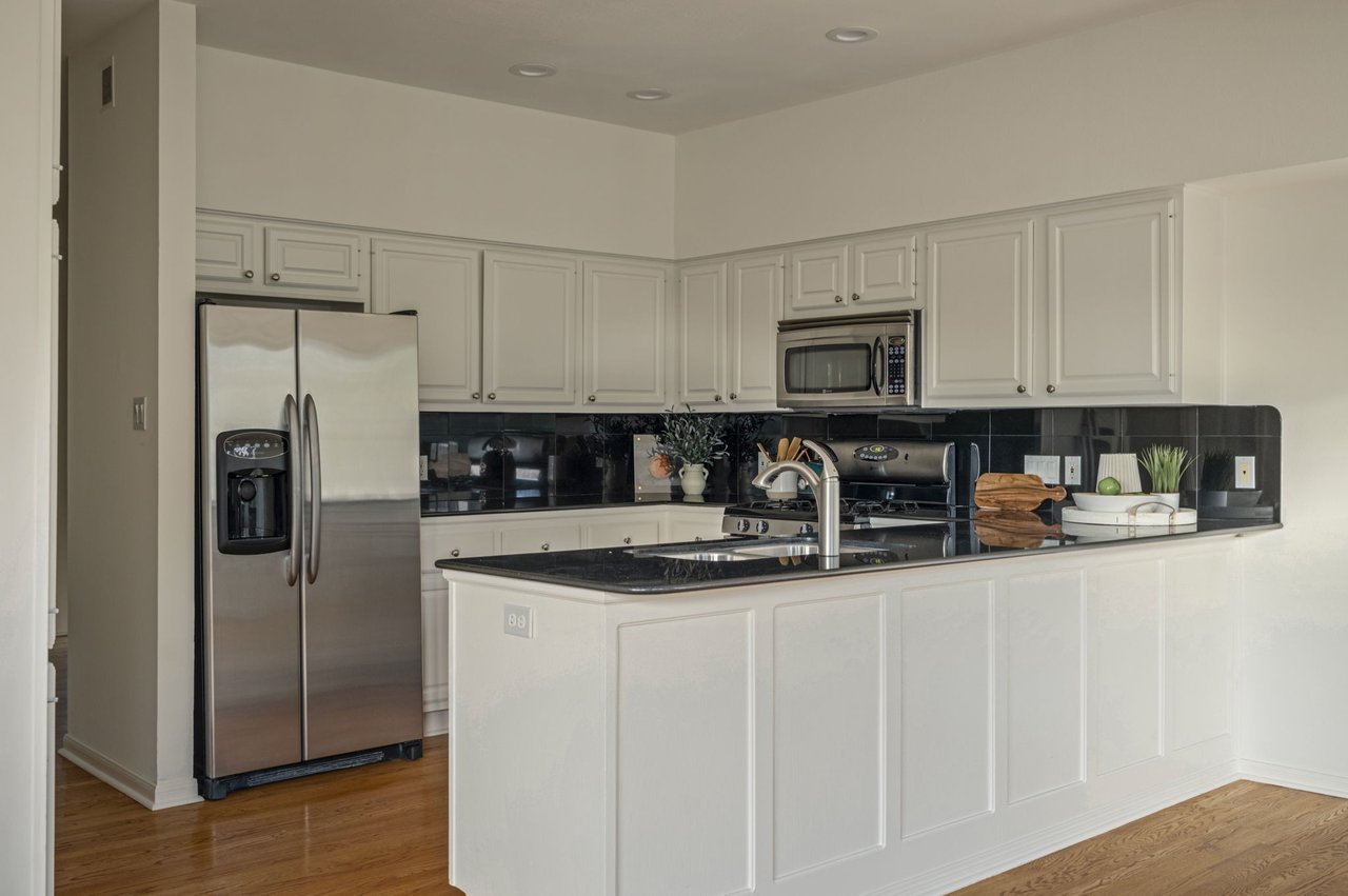Kitchen with stainless refrigerator, paneled peninsula and white cabinets, Winners Circle townhome, Westlake 78746.