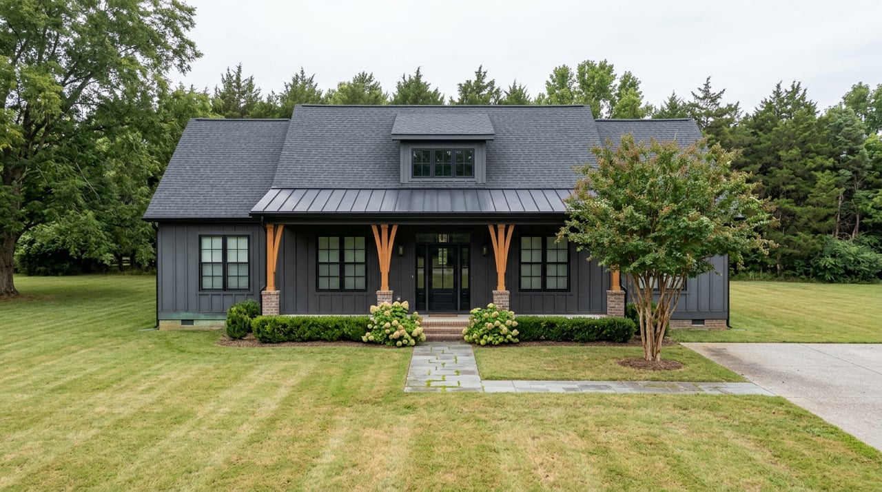 Dark board-and-batten farmhouse with a centered dormer, broad front lawn, and bluestone walkway.