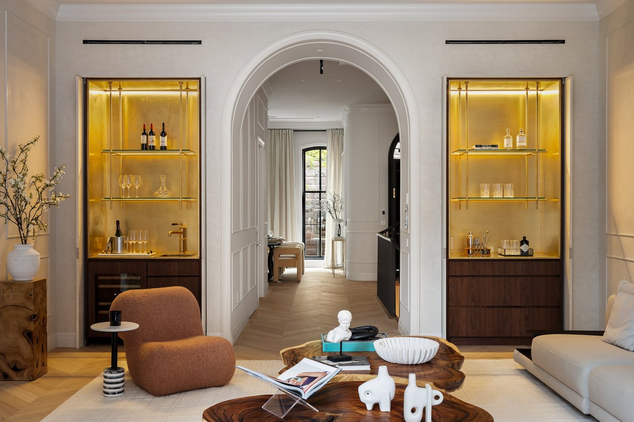 Living room with an arched doorway, glowing bar cabinets, and herringbone flooring.