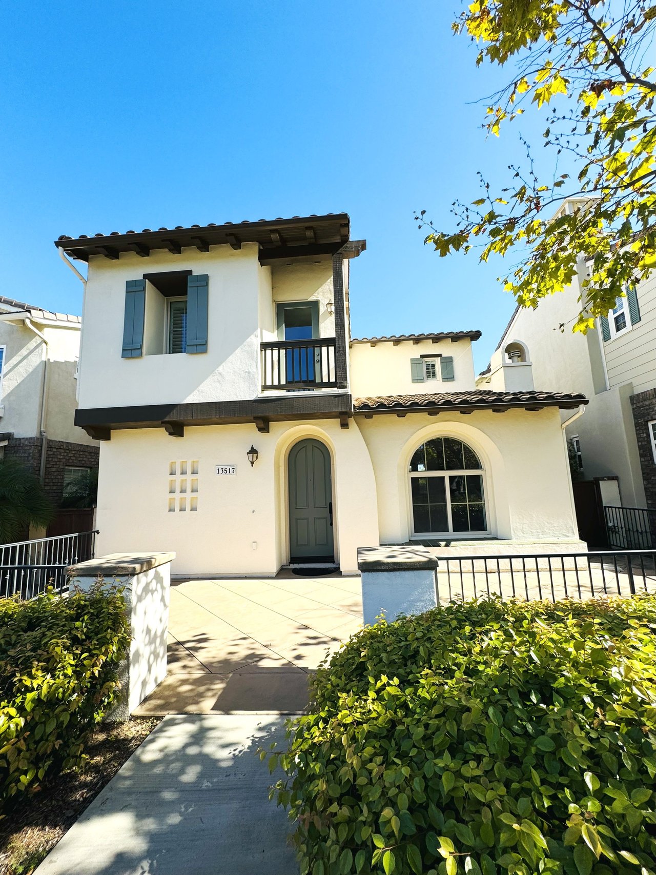 Front exterior view of a renovated Spanish-style home at 13517 Pacific Highlands Ranch, Carmel Valley San Diego 92130, featuring arched entry, balcony, and landscaped walkway.