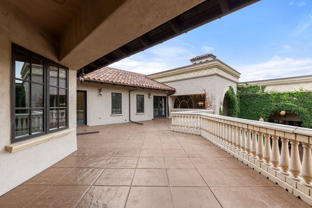 Estate terrace with tiled flooring, a curved stone balustrade, and terracotta roof tiles.