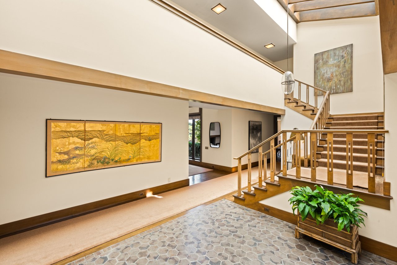 Two-story foyer with a carpeted staircase, wood railings, and a patterned tile floor.