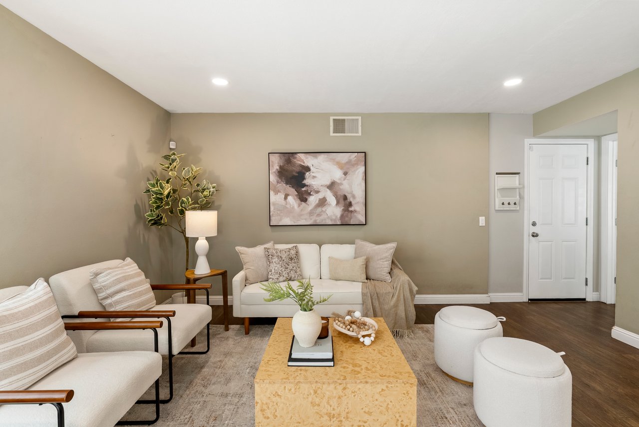 Staged living room with a white sofa, wooden coffee table, and abstract wall art.