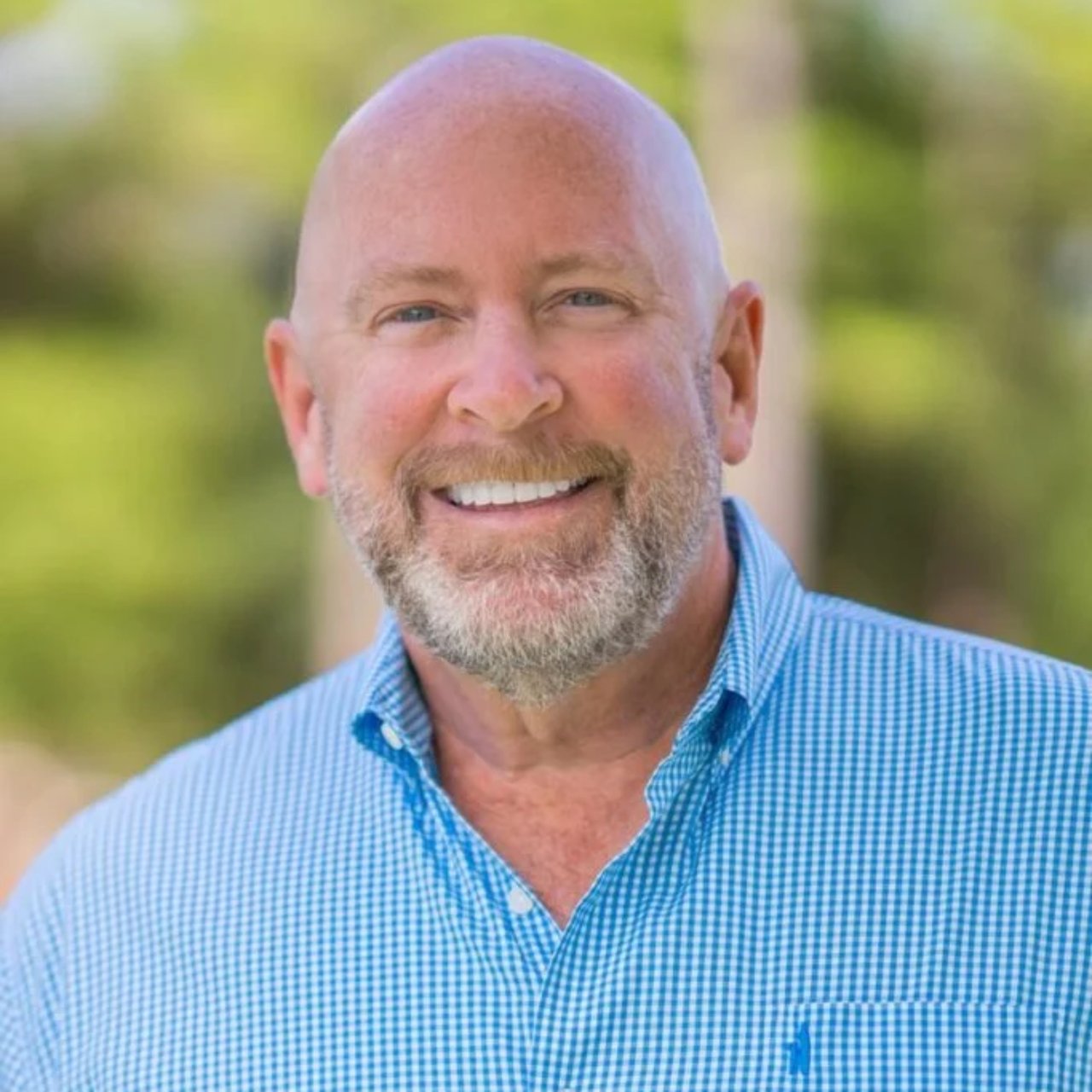 Chris Goger smiling in a blue checked shirt.