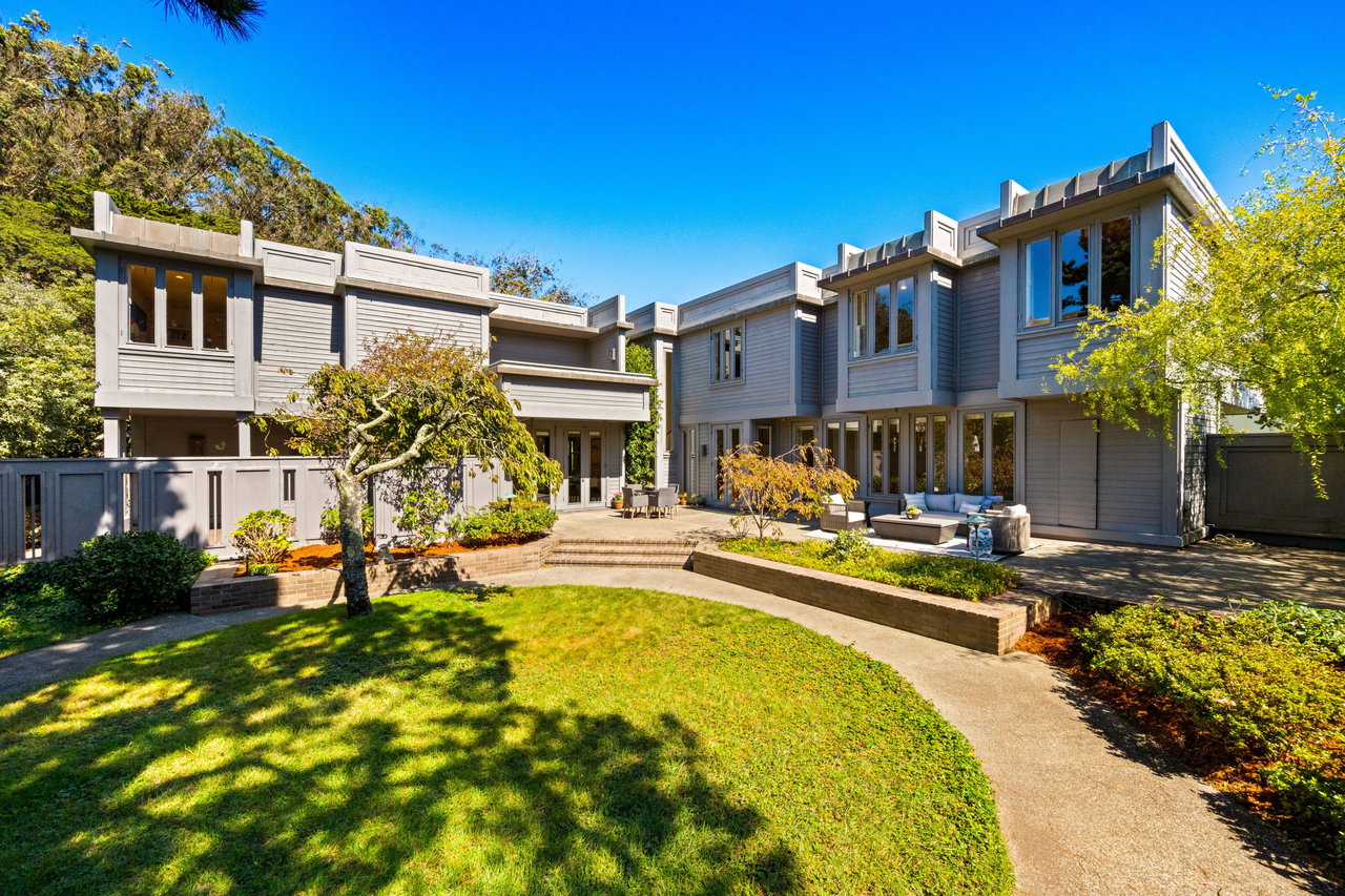 Modern gray home overlooking a landscaped courtyard with a curved path and outdoor seating.