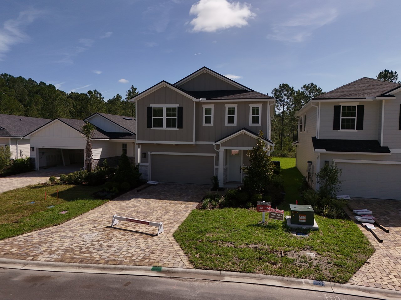 Two-story gray home with white trim, black shutters, and a paver driveway in Elm Ridge Silverleaf.