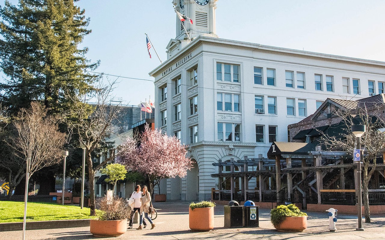 Downtown Santa Rosa’s Empire Building and clock tower beside a sunny plaza.