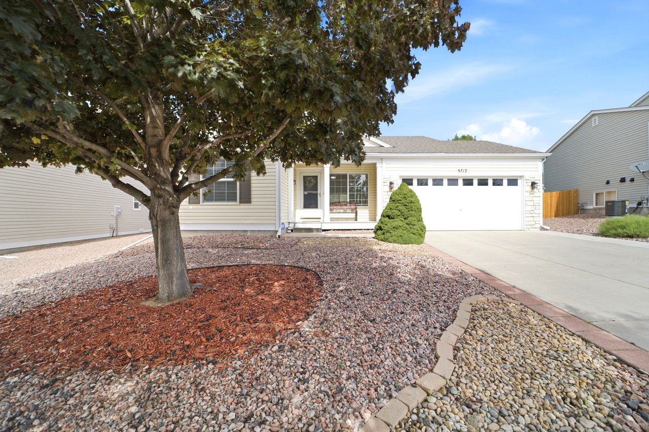 Low-maintenance xeriscaped front yard with mature tree and concrete driveway