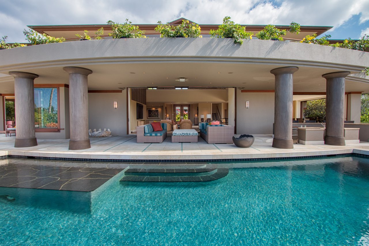 Modern home with a columned covered terrace and turquoise swimming pool.