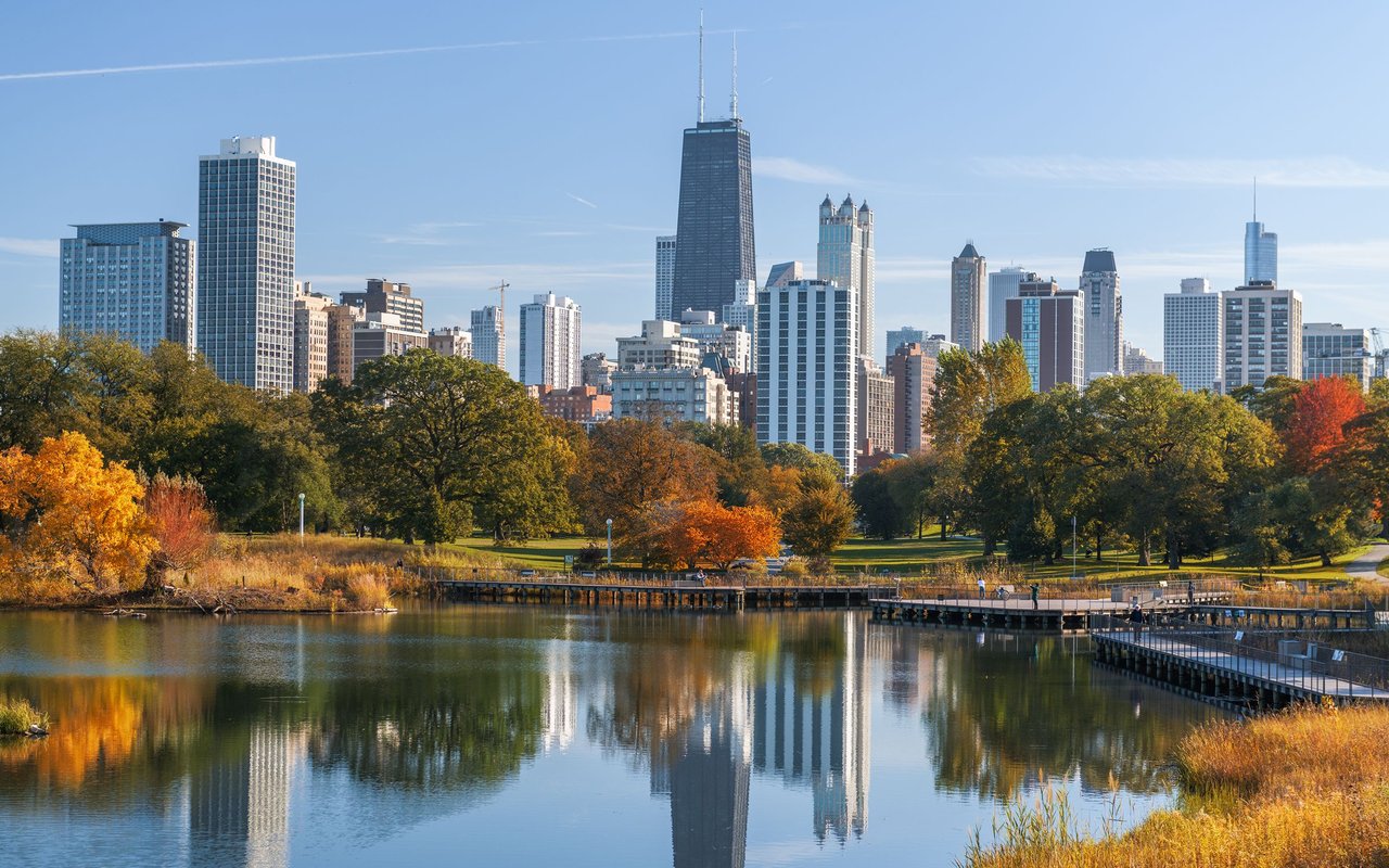 Chicago skyline reflected in a lagoon, with Lincoln Park’s autumn trees in the foreground.