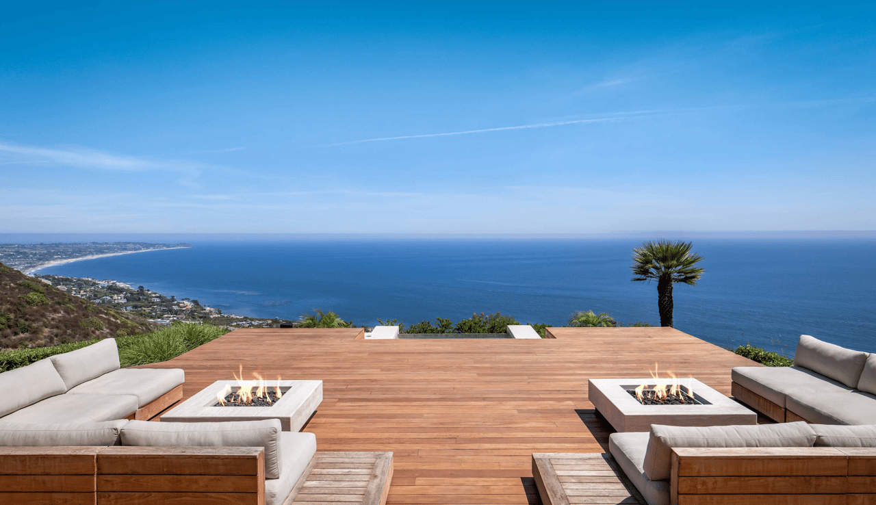 Oceanfront deck with lounge seating and two fire pits overlooking the Pacific coastline.