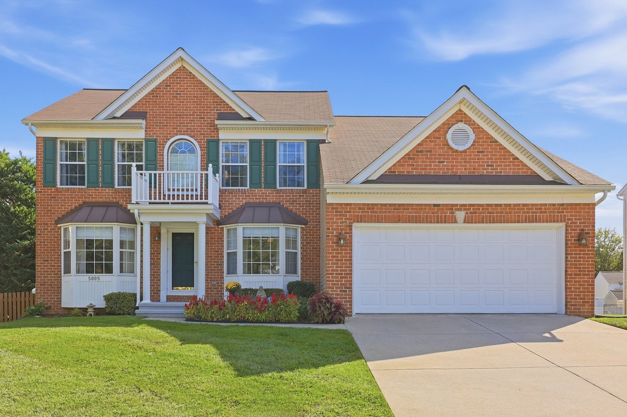 Two-story brick home with green shutters, a front balcony, and attached garage.