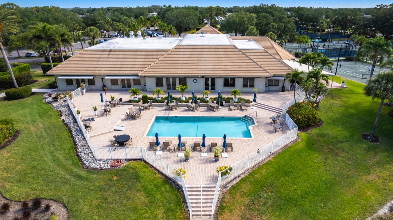 Longshore Lake pool area with lounge seating and adjacent clubhouse in North Naples