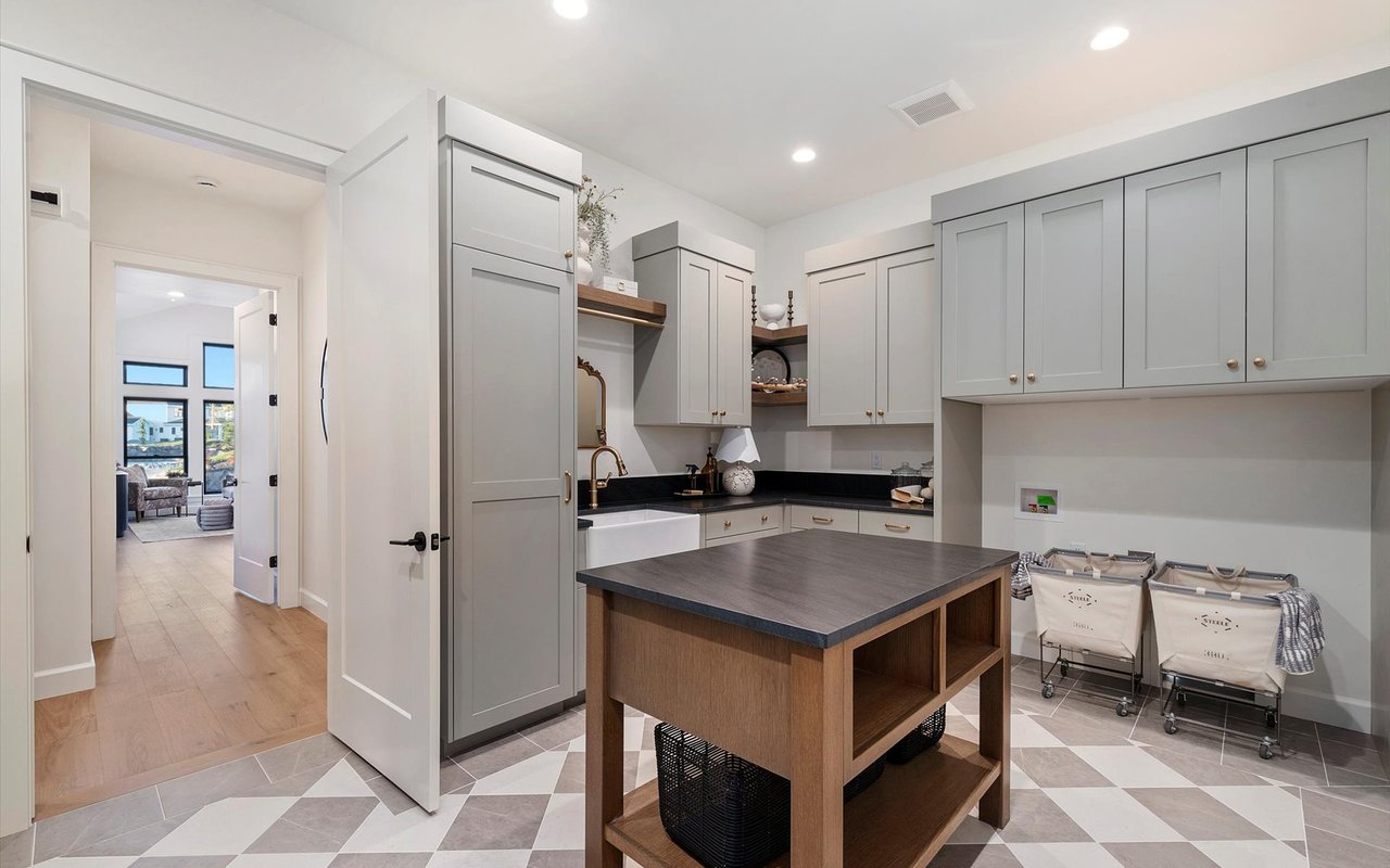 Laundry room with gray painted cabinets, farmhouse sink and an island for folding laundry