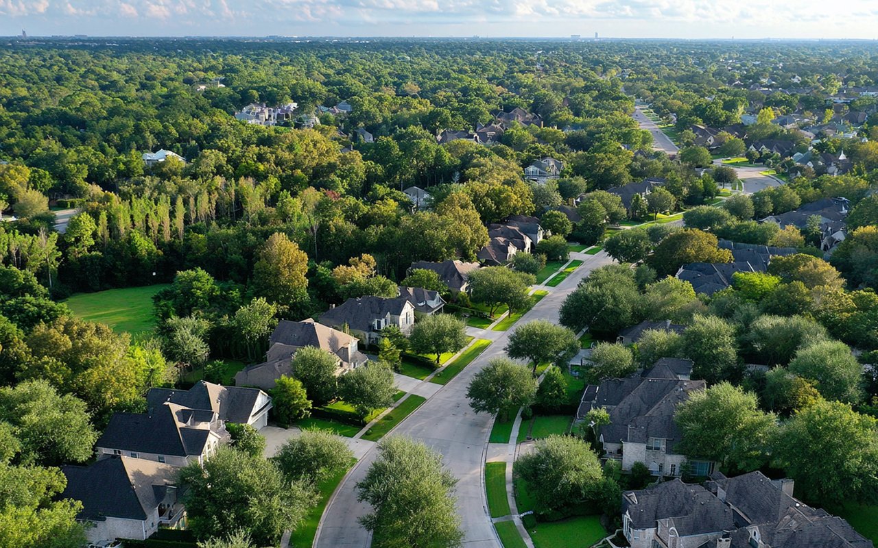 Aerial view of a leafy neighborhood with detached homes and tree-lined streets.