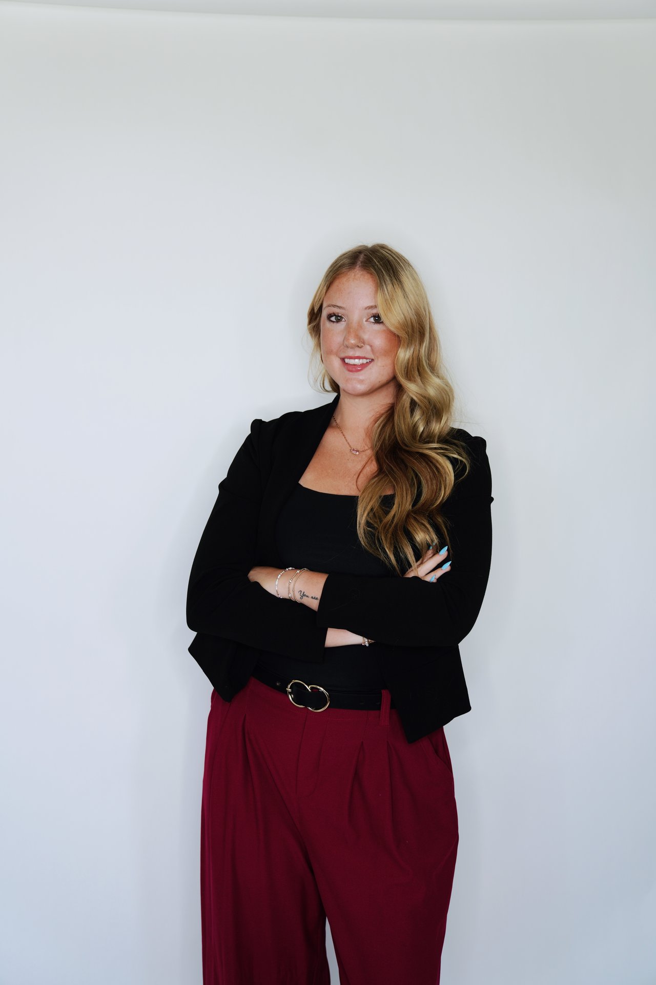 Kylee Humpreys poses with crossed arms in a black blazer and burgundy trousers.