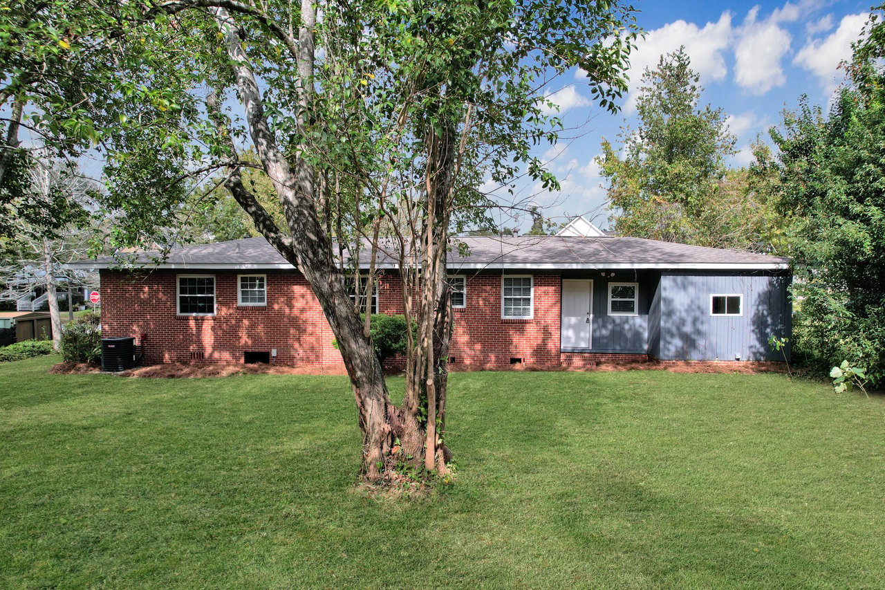 A spacious house surrounded by a large yard and several trees, showcasing a serene and inviting outdoor environment.