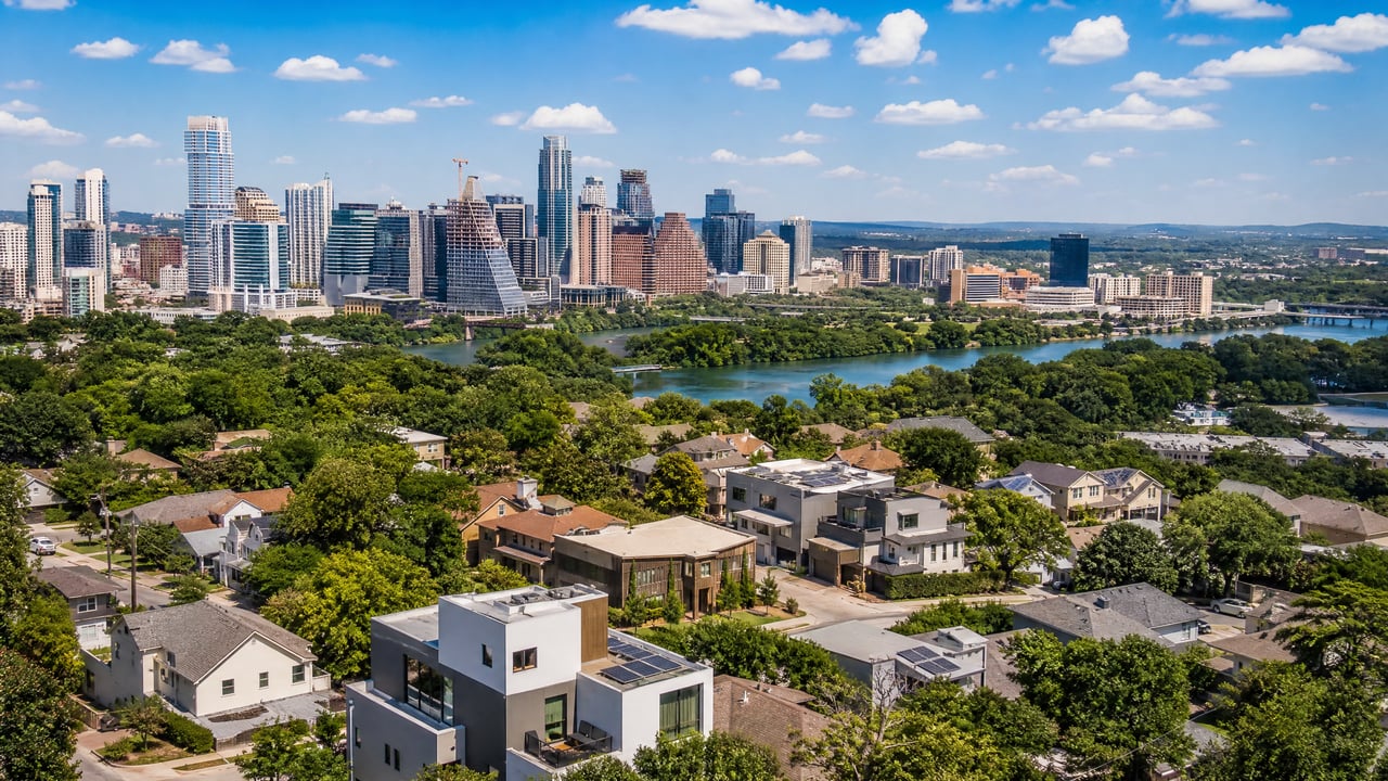 Aerial view of Austin homes, the Colorado River, and downtown skyline.