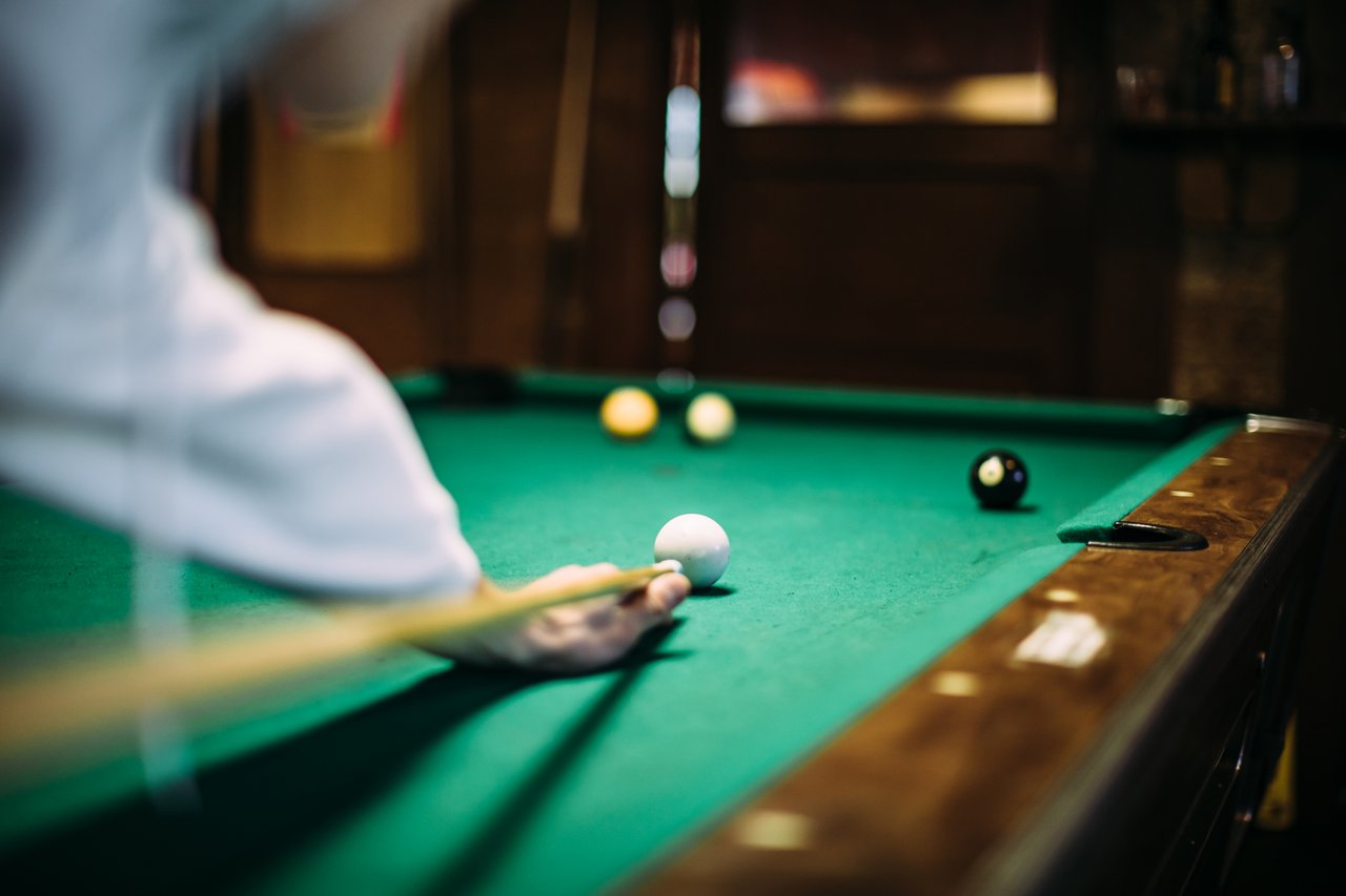 A player lines up a shot on a green pool table.