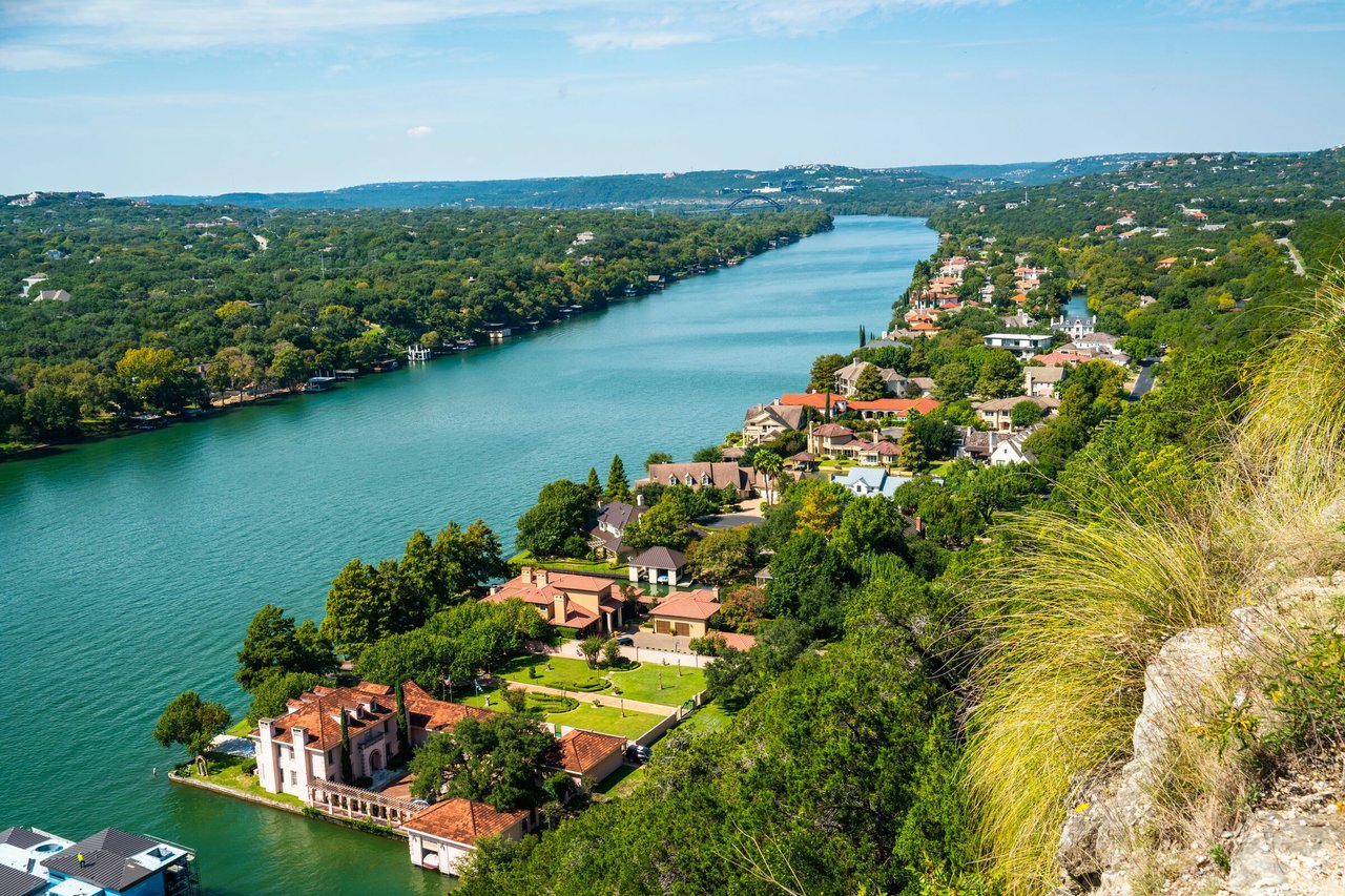 Aerial view of lakeside homes among trees along a broad blue lake.