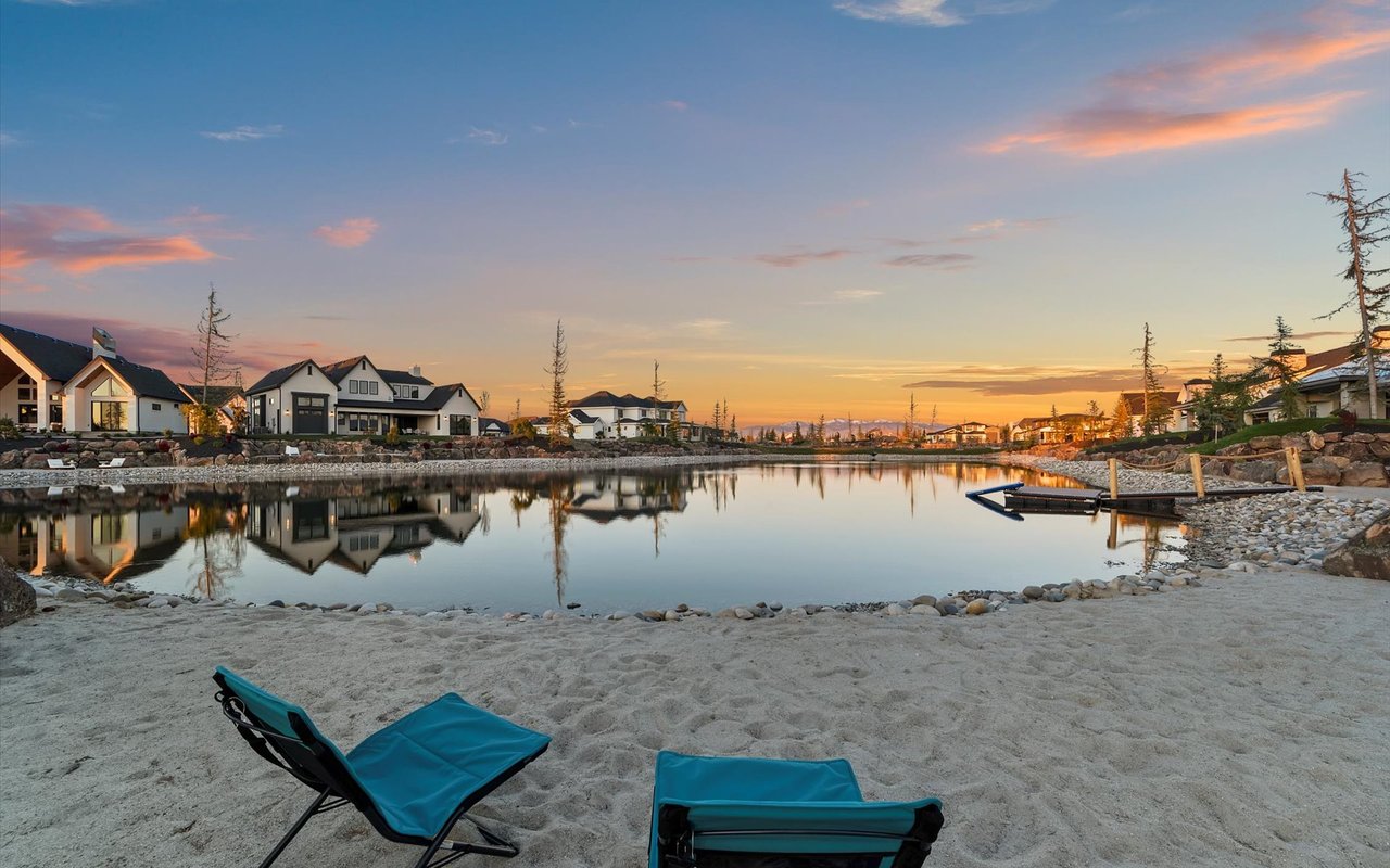 Another angle of the beach, lake and mountains with blue beach chairs and a sunset
