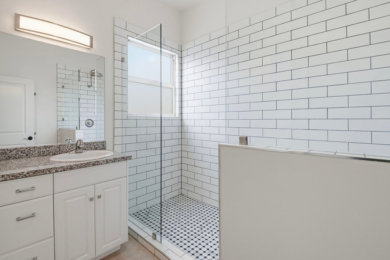 Bathroom with white subway tile, vanity with granite countertop, and tub-shower combo with mosaic tile floor