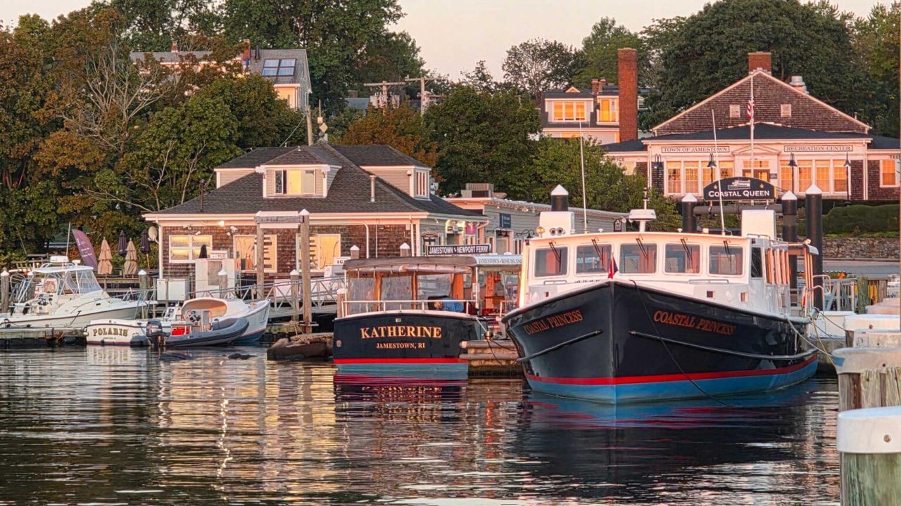 Jamestown harbor at golden hour, with moored boats and the Recreation Center along the waterfront.