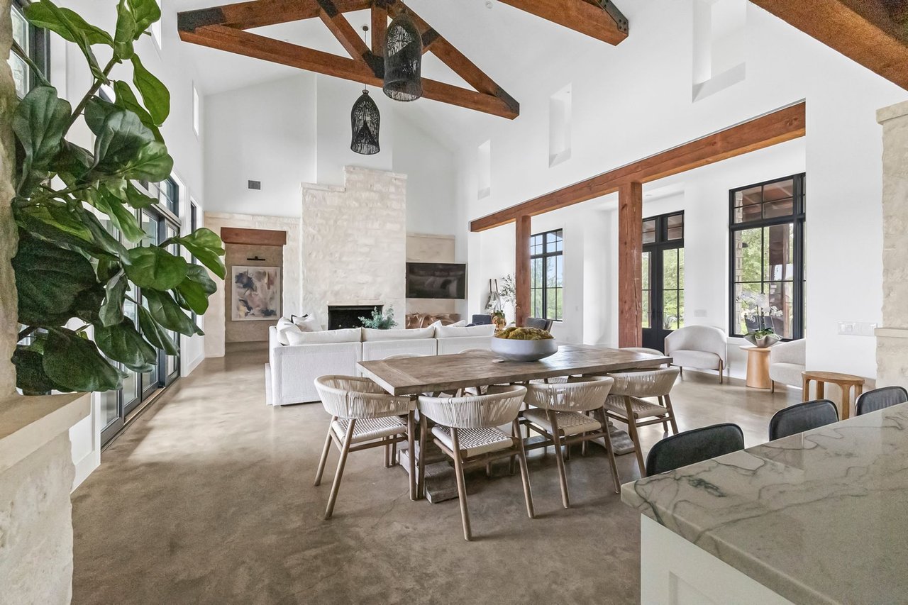 Breakfast nook and vaulted, beamed living area with a fireplace in this Creek Road Ranch home in Dripping Springs, Texas.