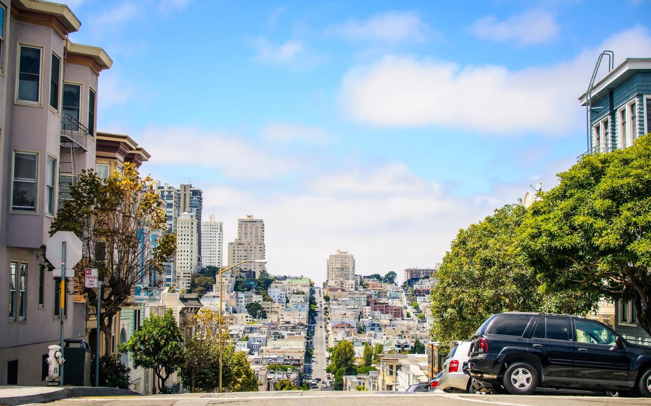Presidio Heights street slopes toward the city, lined with homes, trees, and parked cars.
