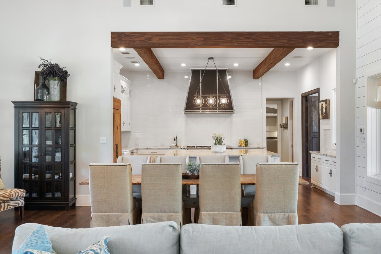 Chef's kitchen at 335 Winning Colors featuring an oversized island, custom vent hood, and beamed ceiling accent, adjoining the breakfast table.