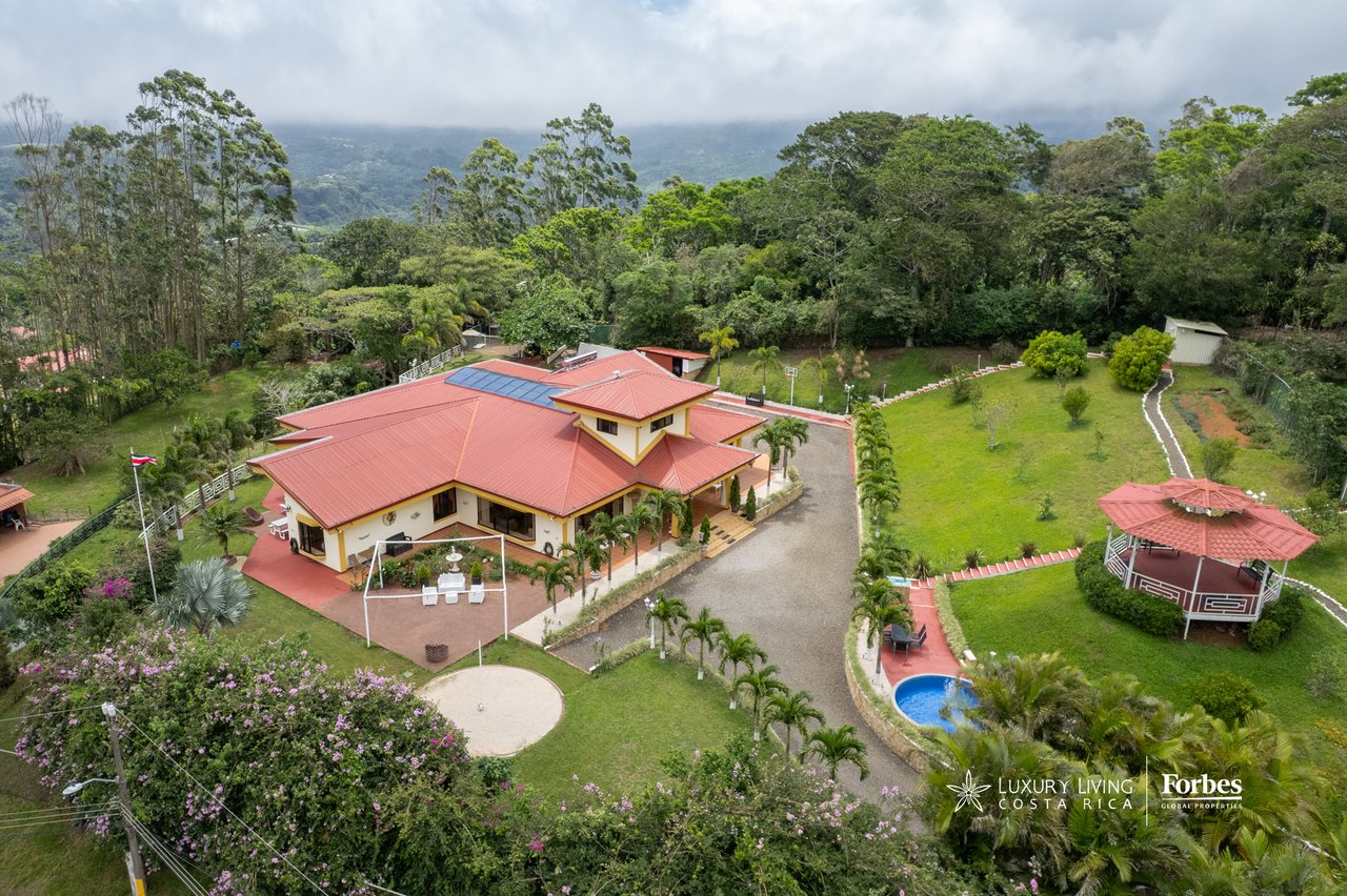 Mountain home with red roofs, landscaped grounds, pool, gazebo, and forested mountain views.