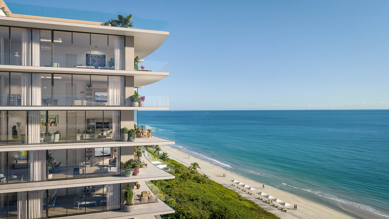 Modern beachfront condominium with curved balconies overlooking a sandy beach and turquoise ocean.