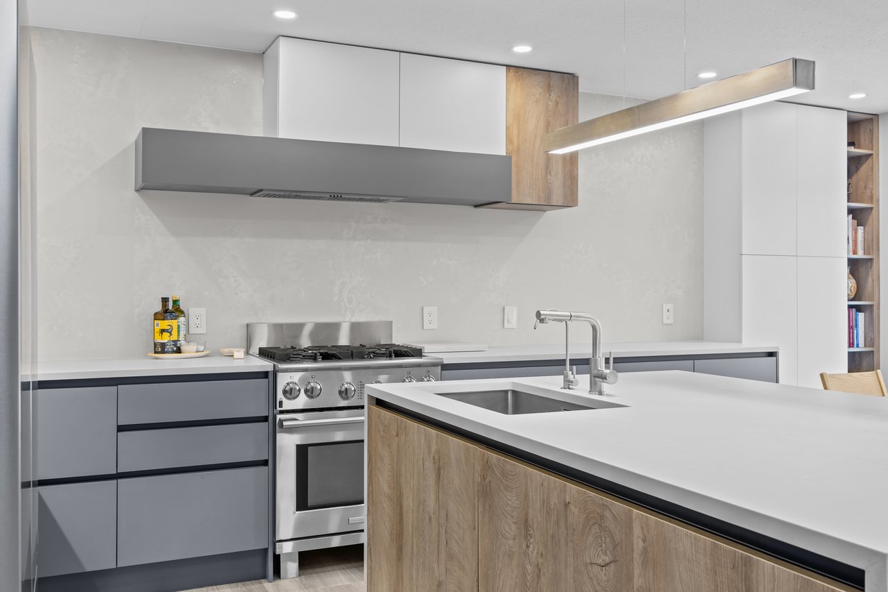 Modern kitchen with a stainless steel gas range and a large wood-front island with sink.
