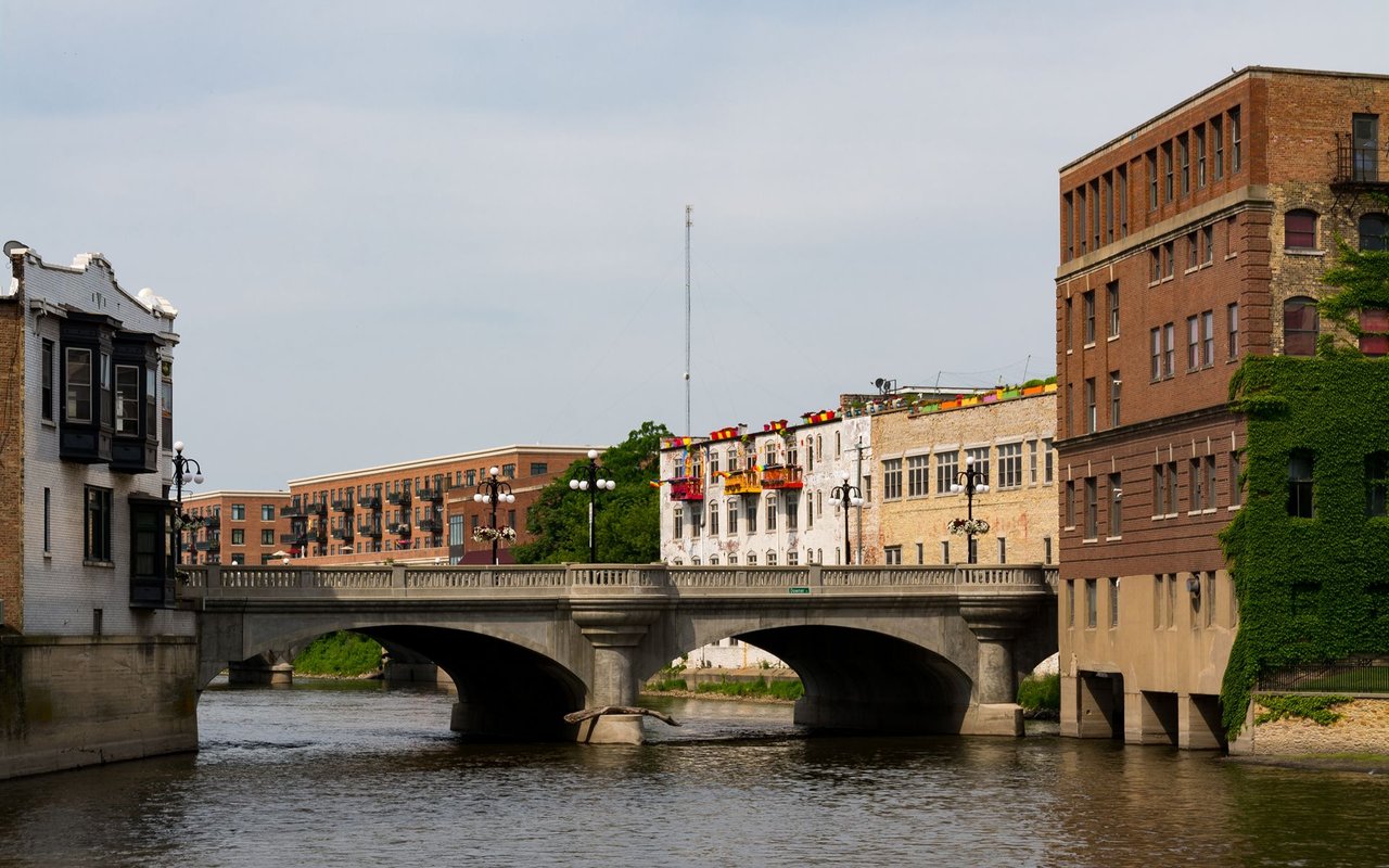 Riverfront bridge crossing between historic brick buildings.
