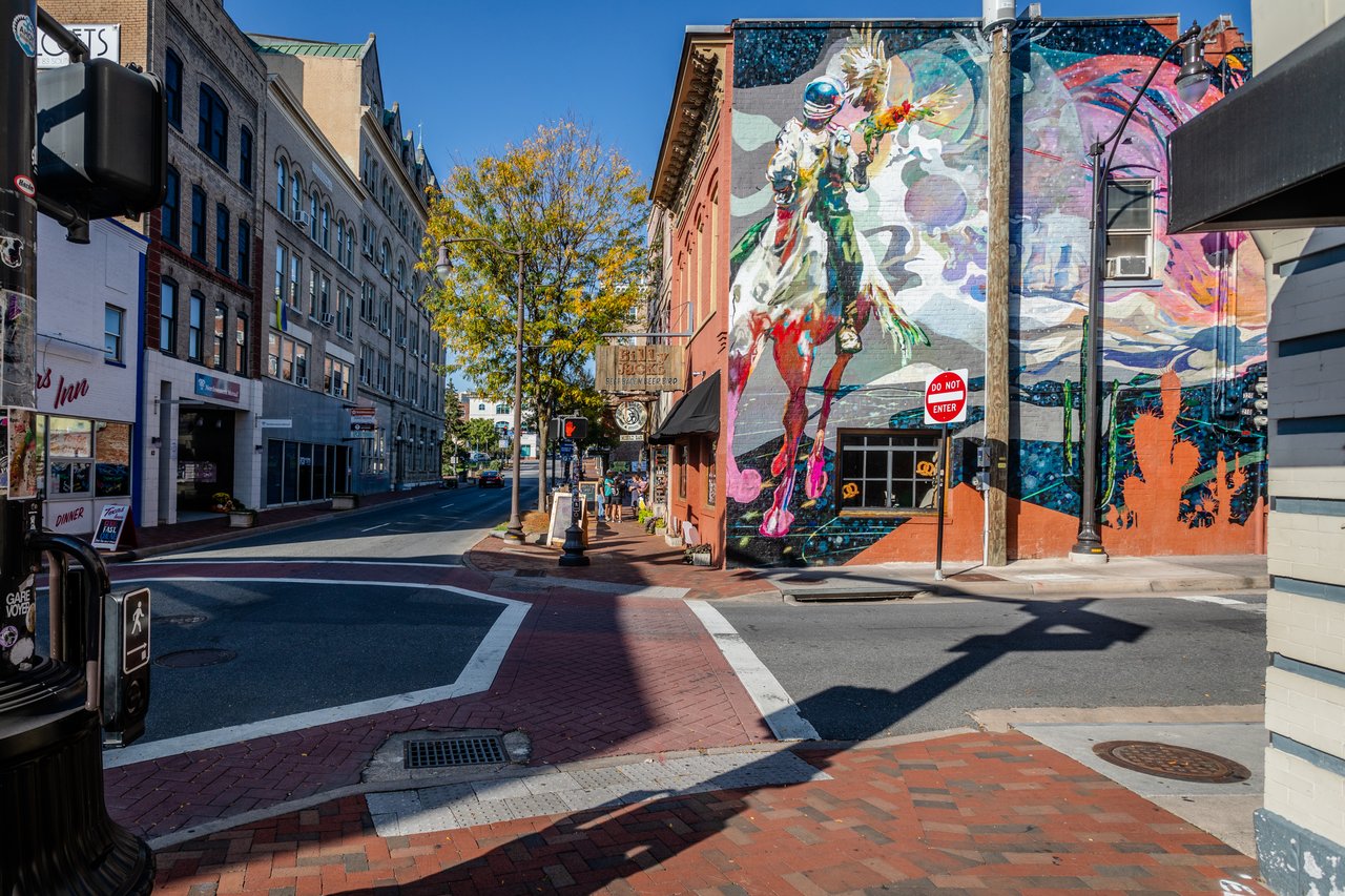 Downtown street intersection beside a colorful mural-covered brick building.