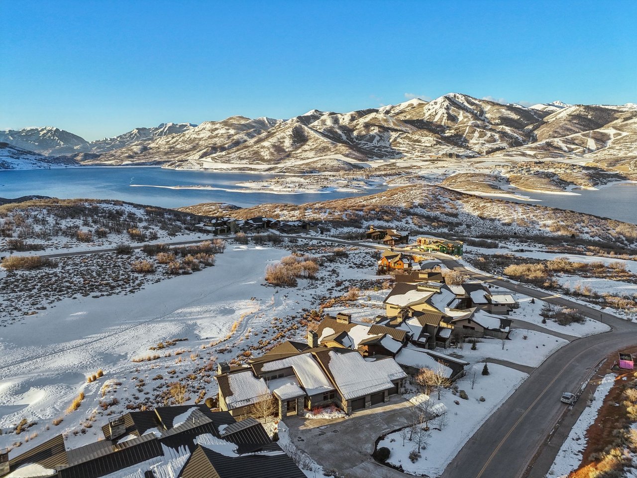 Winter aerial of homes above the Jordanelle Reservoir with Deer Valley ski runs in the distance