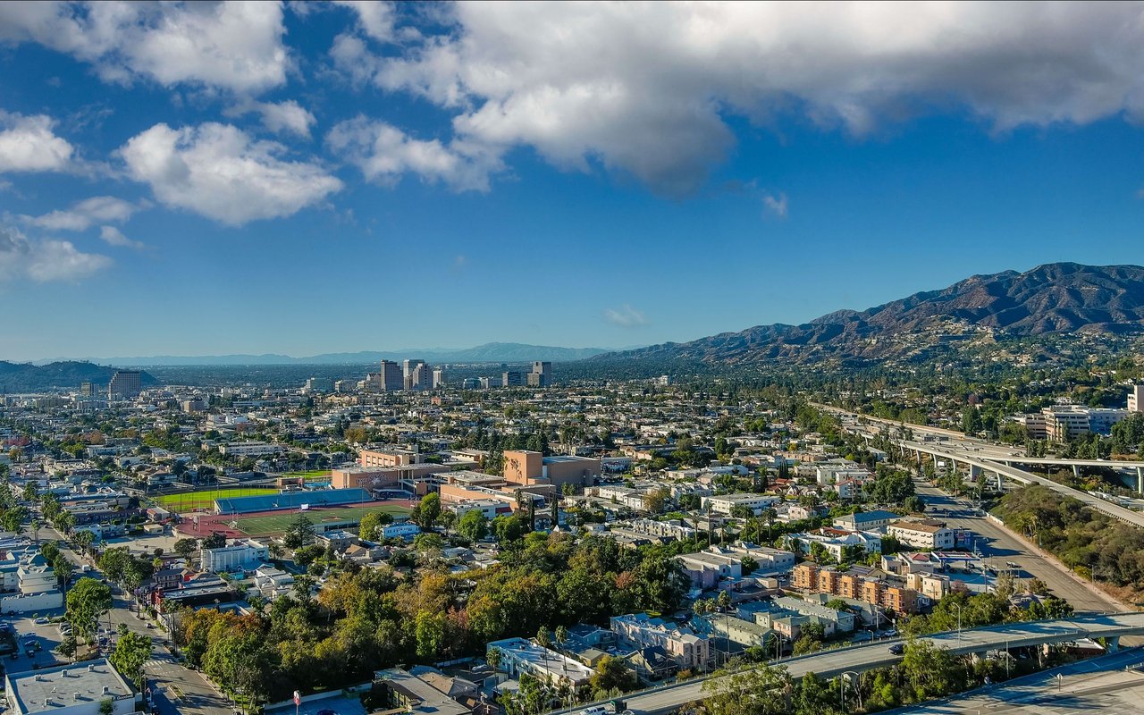 Aerial view of Eagle Rock, with neighborhood streets, sports fields, a freeway, and mountains.