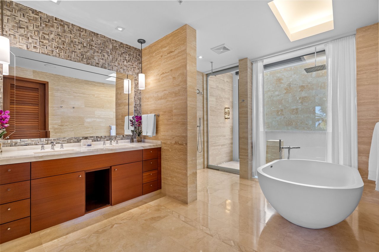 Luxury bathroom with a long wood double vanity, glass shower, and freestanding oval bathtub.