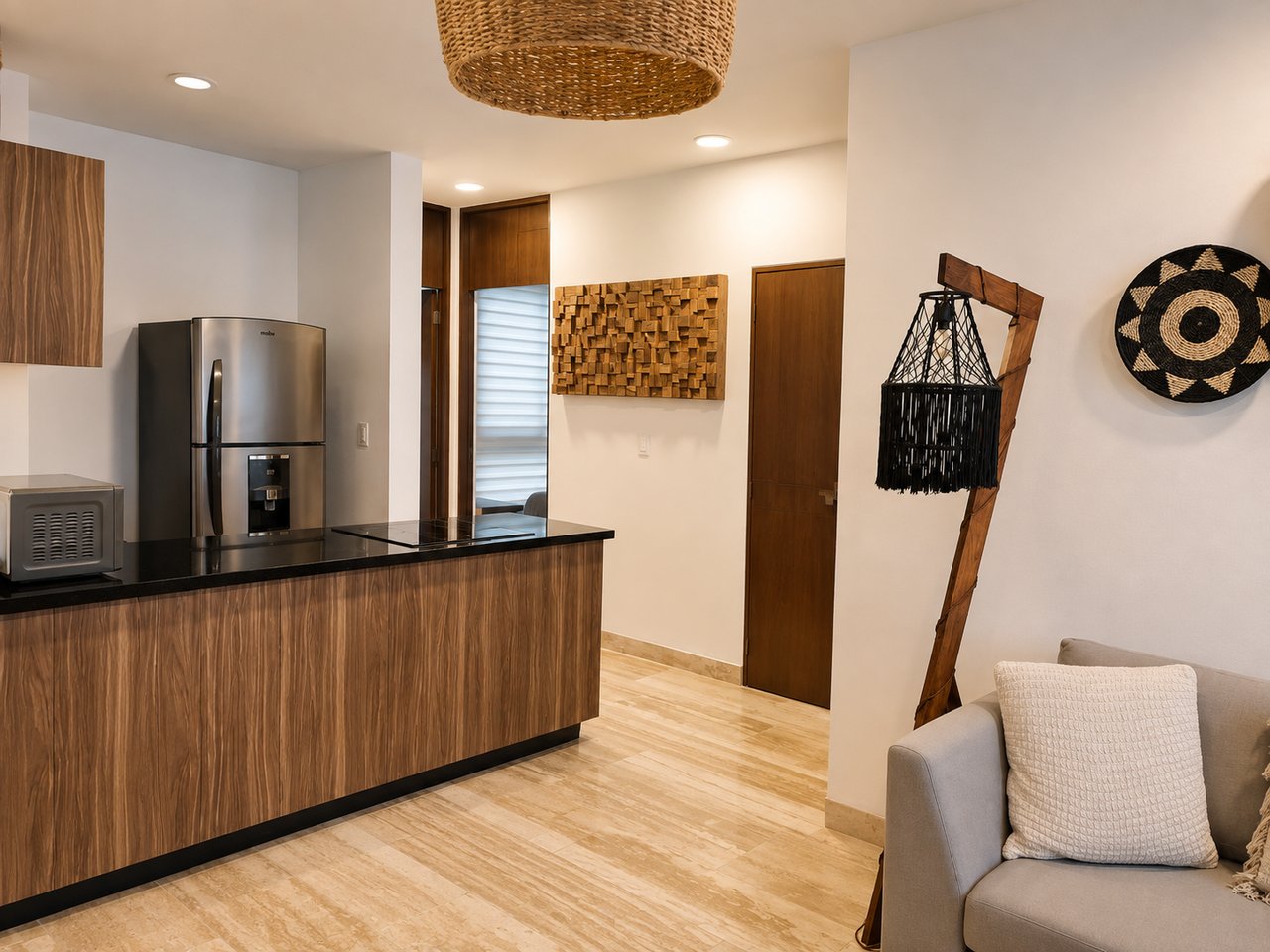 Furnished kitchen with a wood-grain island, stainless steel refrigerator, and woven pendant light.