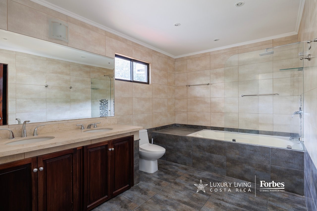 Bathroom with a dark wood double vanity and a bathtub behind a glass shower screen.