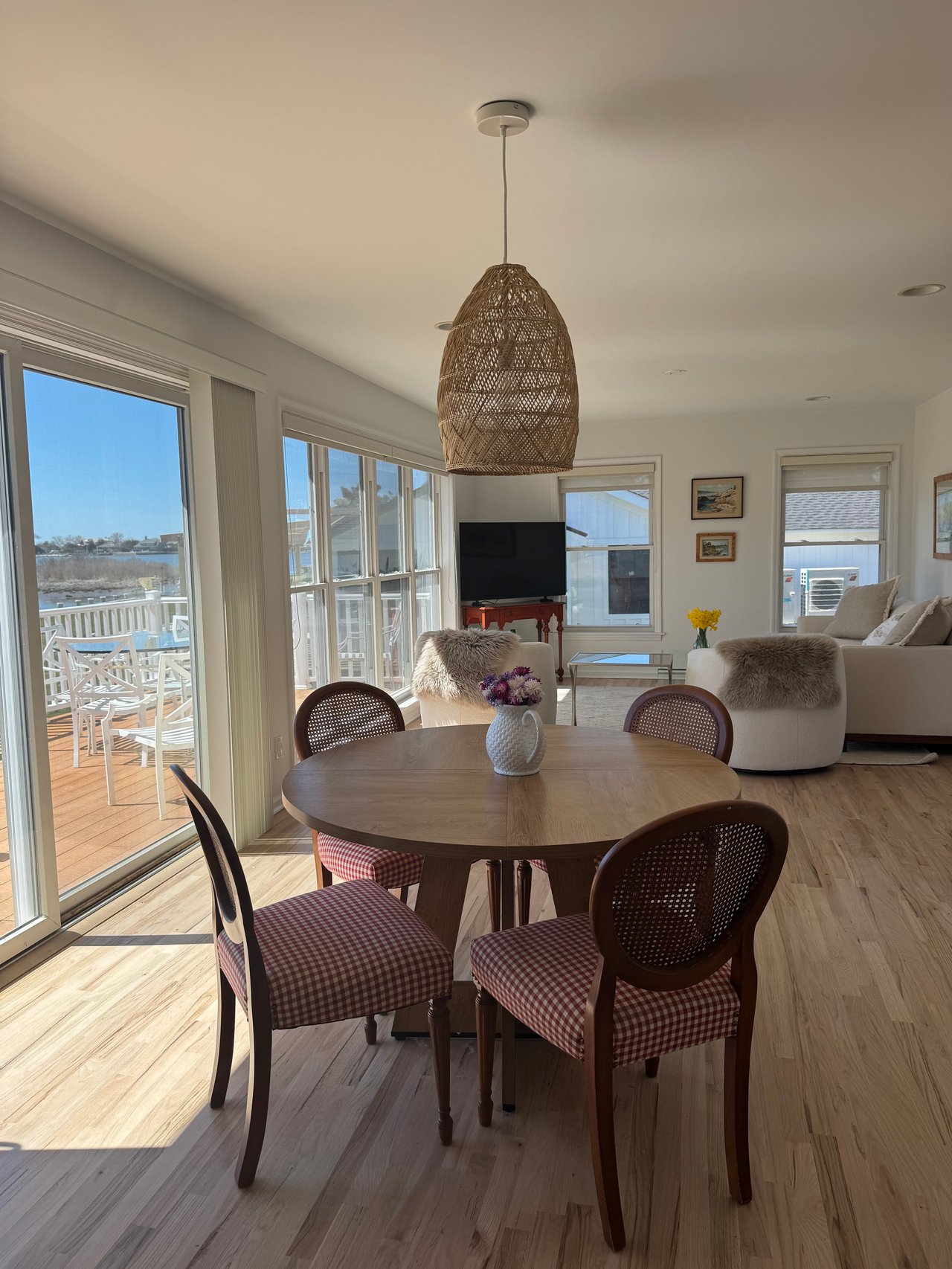 Dining room with a round wooden table and large windows overlooking water.
