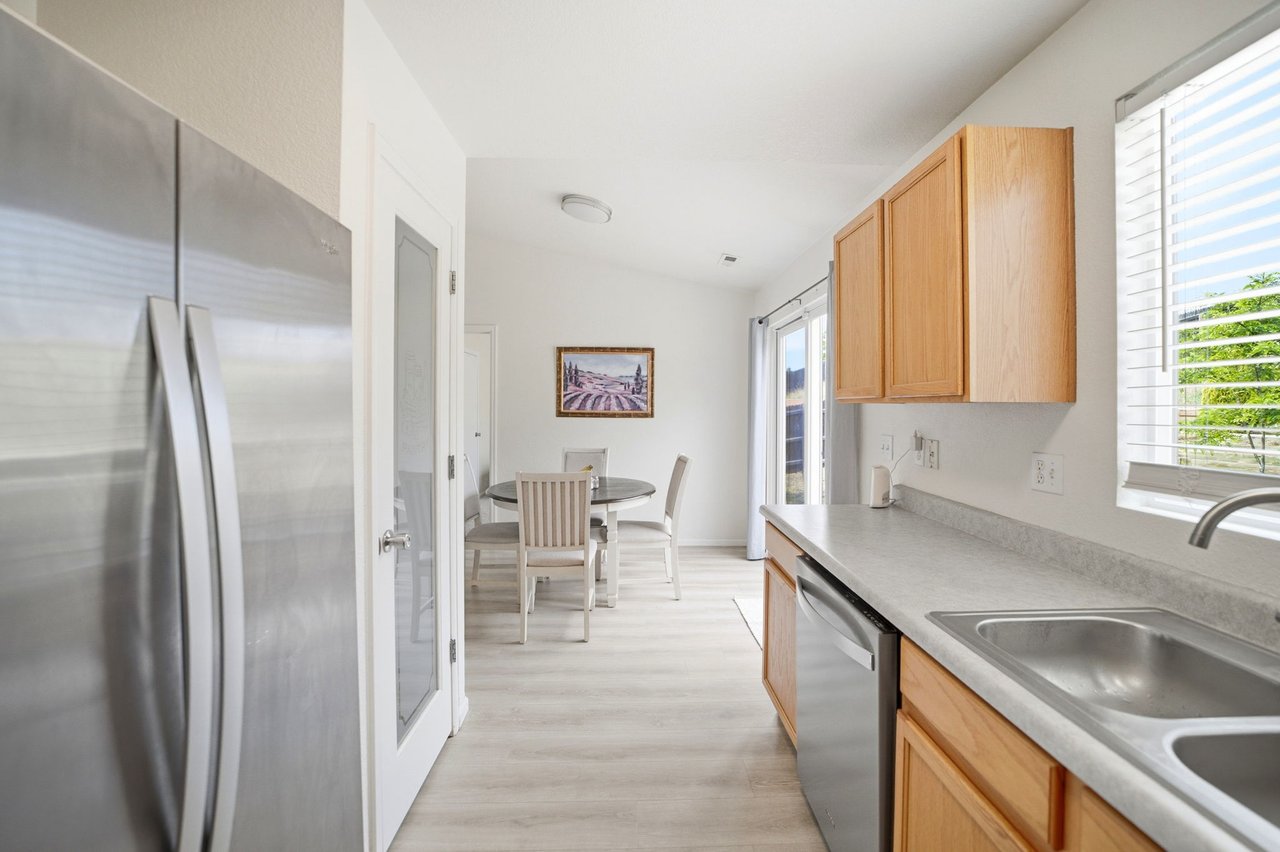 Kitchen with pantry looking out to dining area, vaulted ceilings and walk-out to backyard patio