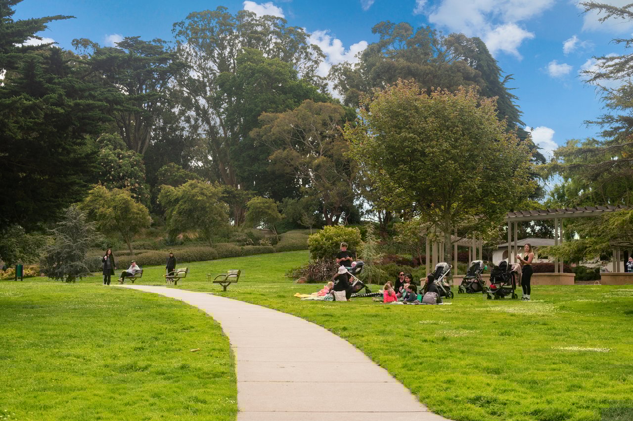 People relaxing in Lafayette Park on a sunny day in San Francisco, illustrating the community and local regulations that influence home sales.